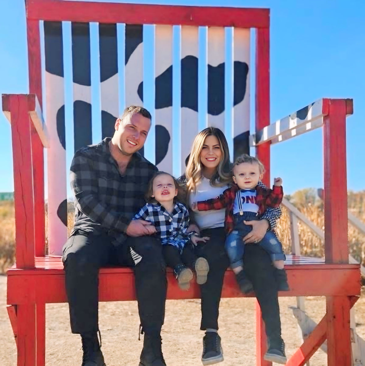 Rose with her family, sitting together on an oversized red wooden chair outdoors