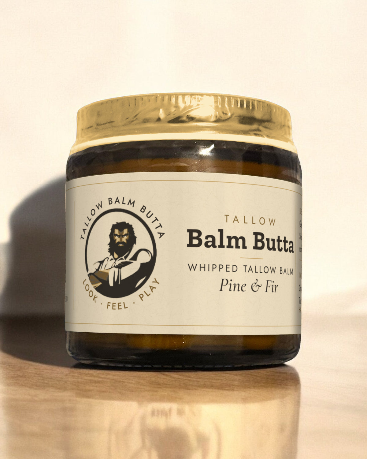 Tallow Roots Co. Pine & Fir Balm Butta whipped tallow balm in a glass jar with gold lid and cream label, sitting on a wooden shelf against a plain wall