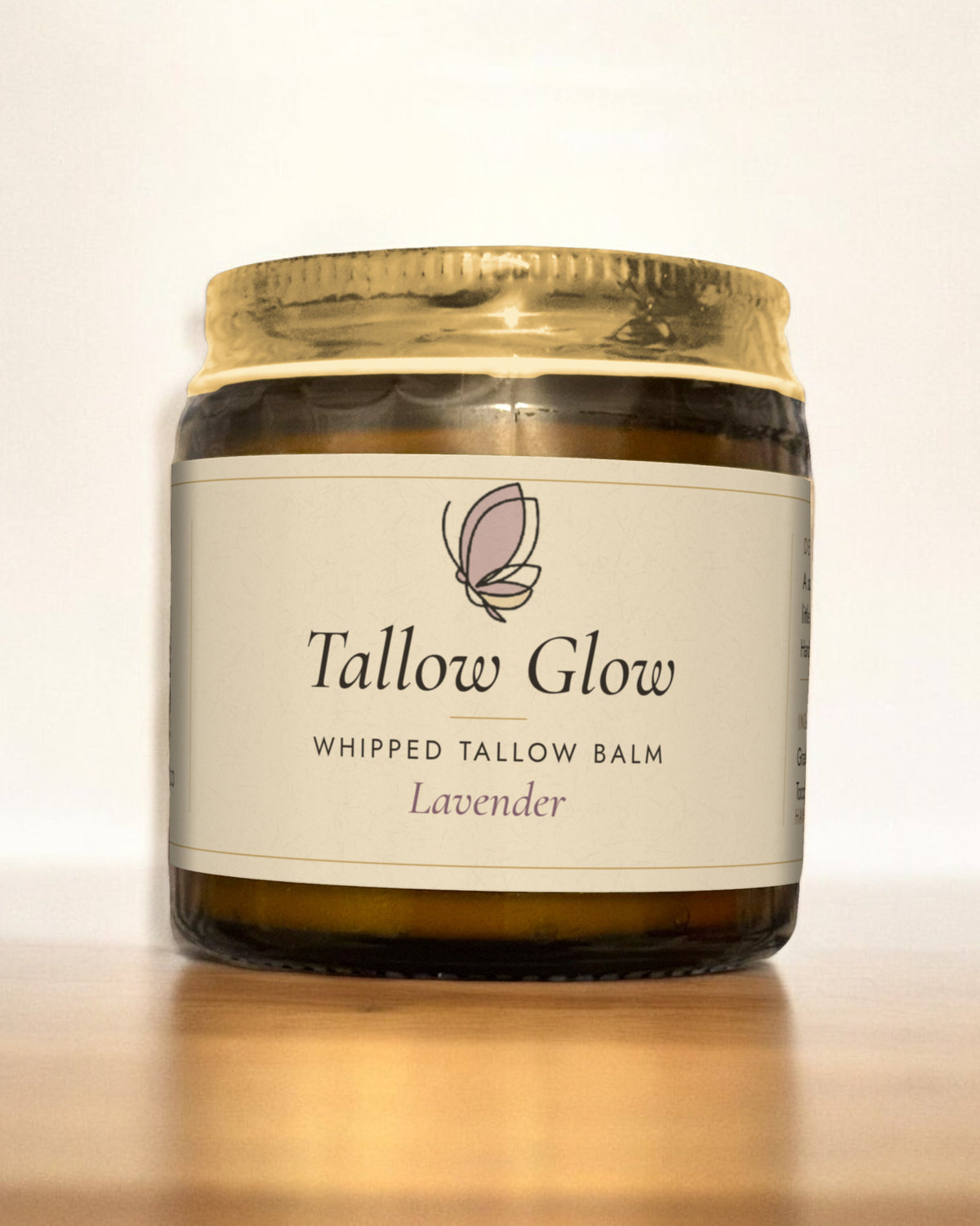 Tallow Roots Co. Lavender Tallow Glow whipped tallow balm in a glass jar with gold lid and cream label, sitting on a wooden shelf against a plain wall